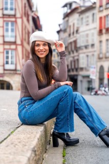Vertical portrait of a cute elegant chic woman sitting in a square posing in the city