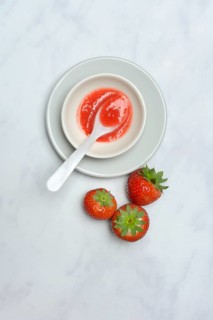 Strawberry sauce in small bowls and strawberries, strawberry coulis