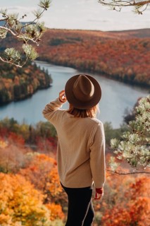 A woman gazes over a vibrant autumn landscape in Quebec, Canada. With colorful foliage and a