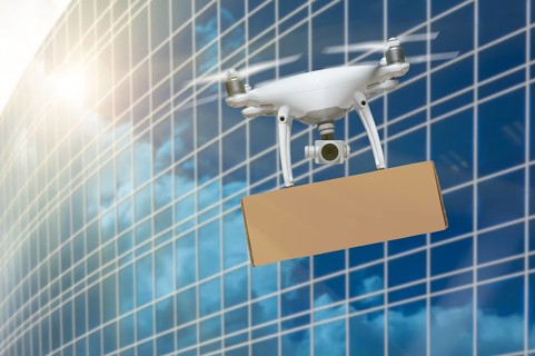 Unmanned Aircraft System (UAS) Quadcopter Drone Carrying Blank Package Near Corporate Building