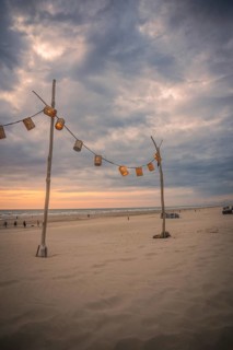 String of lights on wooden post on beach at sunset, Zandvoort, Netherlands
