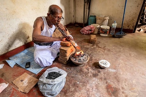 Man in a workshop working concentrated with a blowpipe and bricks, a man burns sapphires in a small