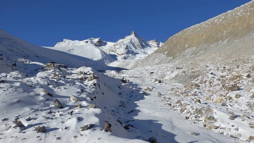 On the way to Thorong La Pass, sunny winter landscape with snow-capped mountains and rocky slopes