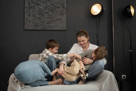 A cheerful family moment with a mother and two children playing on a cozy sofa in a stylish living
