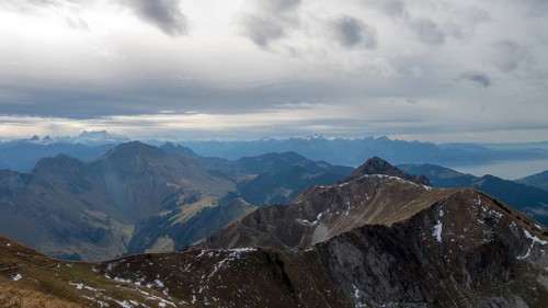 A breathtaking panoramic shot of the french alps and swiss alps under a cloudy sky, capturing the