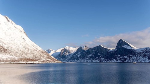 A breathtaking winter view of the Mefjordbotn fjord in Norway, showcasing snow-covered mountains