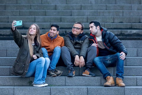 A caregiver and three young men with intellectual disabilities take a fun selfie in an urban
