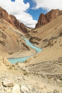 A serene river winds through the barren landscape of the Himalayan region near Phuktal Monastery,