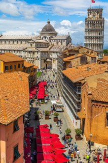 Above the rooftops of Pisa, behind the Cathedral of Santa Maria Assunta and the Leaning Tower, Via