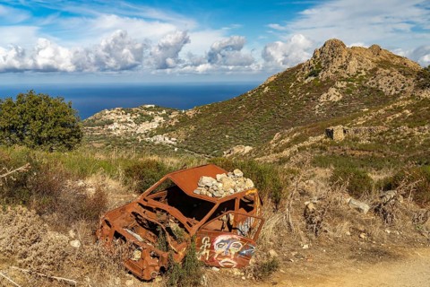 Car wreck in the Balagne countryside and the village of Corbara, Corsica, France