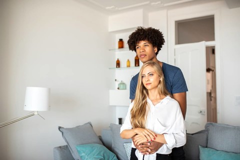 A couple shares a tender embrace in their stylish living room. Soft lighting and modern decor