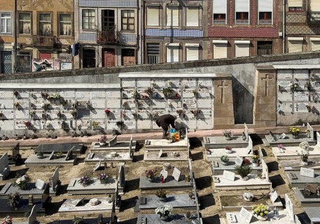 Cemitério da Lapa, Lapa cemetery, a person tending a burial ground, beyond the wall the houses of
