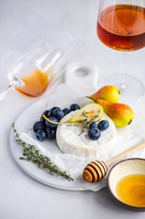 A delectable cheese and fruit platter featuring creamy brie cheese, ripe pears, fresh blueberries,