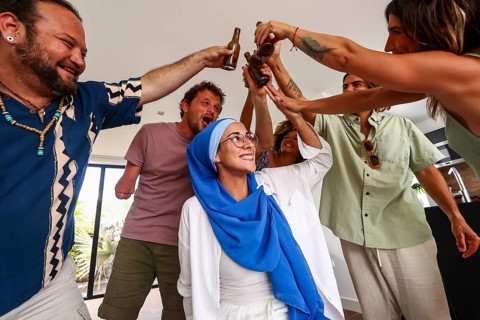 A multiethnic group of diverse friends cheerfully raise bottles in celebration, enjoying each
