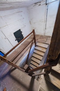 Staircase view from above with wooden banister and weathered old building character, Prison Museum,