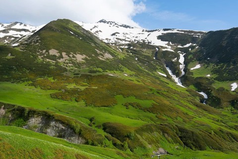 Green mountains with waterfalls and snow under a blue sky, Zagari Pass, Svaneti, Greater Caucasus,