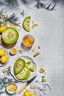 Top view of fresh melon and lemon slices on a tiled textured background. Arranged creatively, the