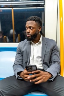 Young businessman commuting on a subway train, using a smartphone to stay connected and engaged