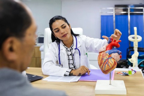 A caring young female doctor attends to an elderly male patient in a warm and professional Latin