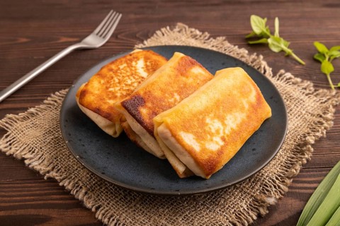 Fried crispy pancakes with meat and cheese on brown wooden background and linen textile. side view,