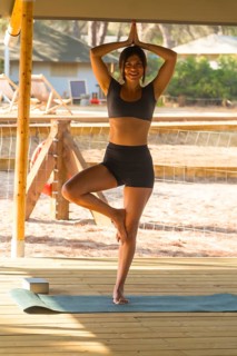 Young woman practicing yoga in tree pose, showcasing balance and mindfulness on a wooden deck