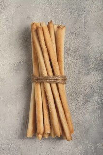 Stacks of crispy bread sticks tied with twine on a textured background