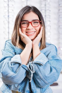 Happy female customer modeling glasses in an optical store. Happy teen girl in eyeglasses on a