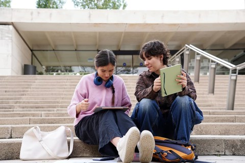 Two teenagers, a non-binary genderqueer individual and a female, are focused and engaged in
