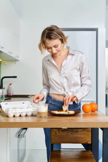 Young woman dips toast in fried egg