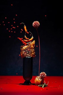 Dynamic display with chilies peppers and honeycomb on a black background. Floating red berries