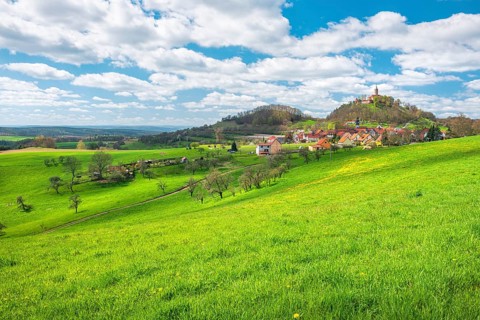 View of hilly landscape with the village of Seitenroda and Leuchtenburg in spring, in front a green