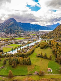 Aerial view of villages in a picturesque mountain landscape with river and wide sky, Interlaken,