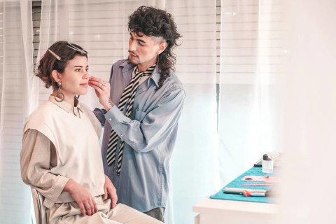 Professional makeup artist applying foundation on a model's face in a bright, modern beauty salon,