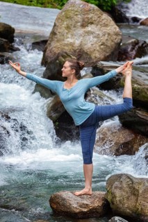 Yoga outdoors, woman doing yoga asana Natarajasana, Lord of the dance balance pose at waterfall in