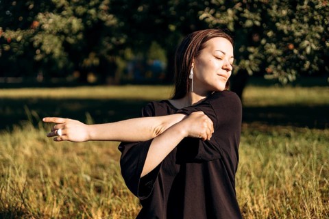 A teenage girl enjoys a peaceful morning in the garden, stretching her arms and embracing the