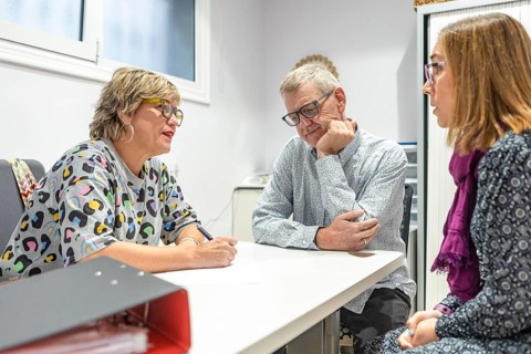 In an office, a women and a couple with intellectual disabilities are engaged in a discussion,