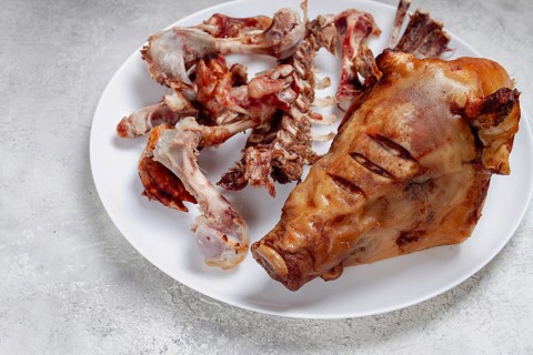 Roast pork head, with remnants of bones and meat, on a white platter, no people, close-up
