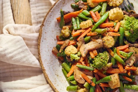 Plate of stir-fried mixed vegetables with green beans, carrots, baby corn, romanesco and mushrooms
