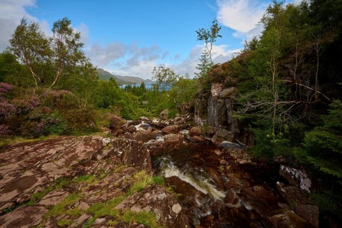 Water flows over rocks in a wooded area under blue skies, Victoria Falls, Slattadale, Achnasheen,