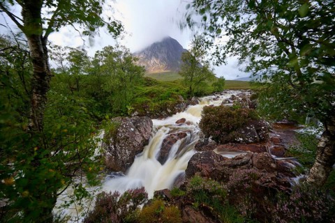 Beautiful waterfall surrounded by green vegetation with an imposing mountain in the background and