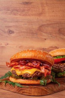 Burger with beef and bacon, with arugula and caramelized onions, pickles, sauce, homemade, no