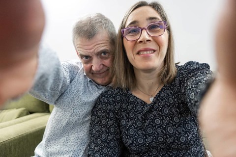A mature couple with intellectual disabilities is joyfully taking a selfie while sitting on a cozy