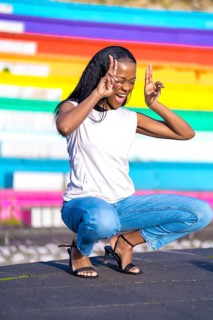 Vertical side view of a cool african woman gesturing victory with hands in a park