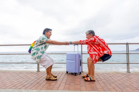 Two mature women, joyfully and excited holding hands, ready for their summer holidays by the sea.