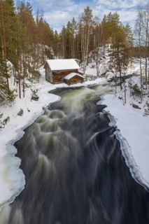 Old wooden Myllykoski water mill along the river Kitkajoki in winter, Oulanka National Park,