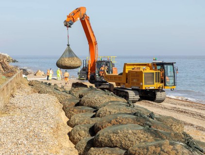 Emergency coastal defences work placing rock bags on beach to protect property, North Sea coast,