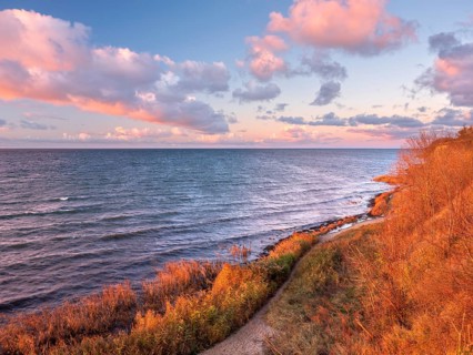 Natural coastal landscape on the Baltic Sea in the last evening light, glowing pink clouds, view of