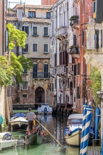 Venetian gondola with gondolier travelling on the canals of Venice, Venice, Italy