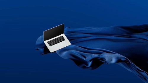 A sleek laptop is placed atop smooth fabric, showcasing its lightweight design against a rich blue