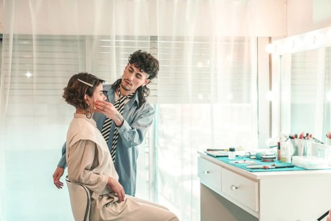 Professional makeup artist carefully applying foundation on a model's face, preparing her for a